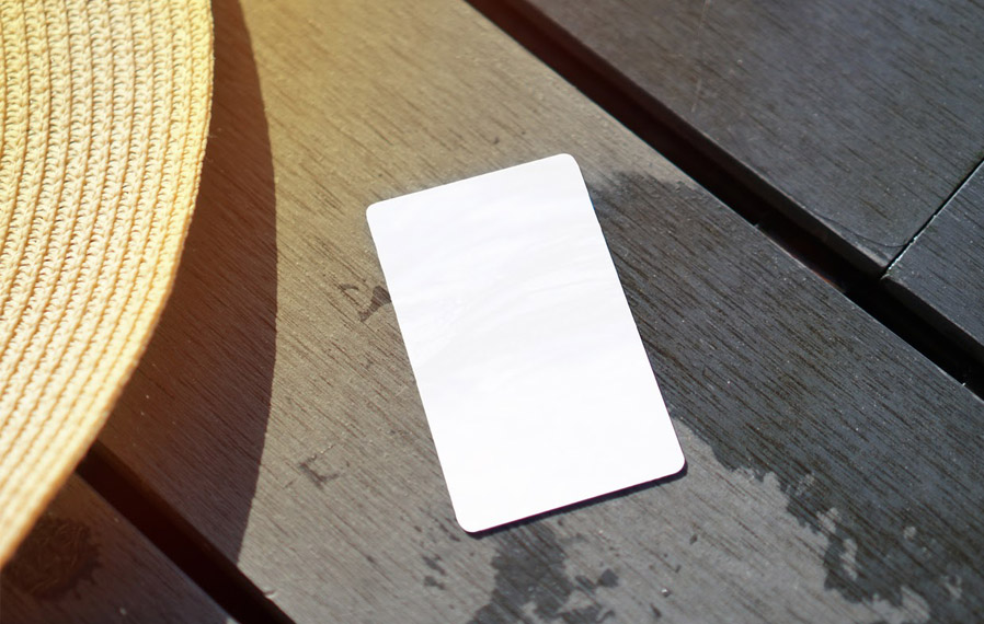 Don't forget your pool pass to to take a refreshing swim at The District at Saxony Apartment Homes. Summer hat and key card on a deck floor.